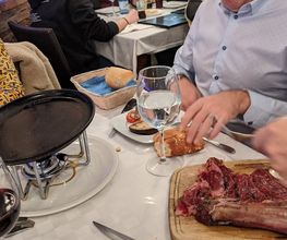 Personas en un restaurante con carne cruda y vino sobre la mesa.