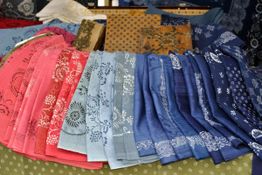 Bunte Stoffe mit floralen Mustern liegen gefaltet auf einem Tisch aus.