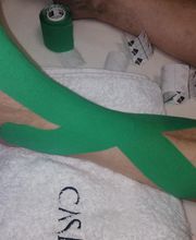 Vendaje kinesio verde en el pie y pierna sobre una toalla blanca.