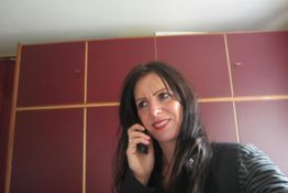 Eine Frau telefoniert lächelnd in einem Raum mit roten Wänden.