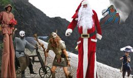 Personen in Kostümen: Weihnachtsmann, Wikinger, Ritter und weitere vor einem Felsenhintergrund.