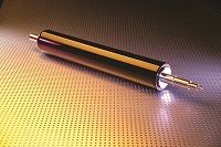 A shiny, metallic industrial roller on a perforated surface, lit by soft, colored lighting.