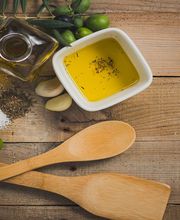 Olio d'oliva, spezie, aglio e cucchiai di legno su tavola rustica di legno.