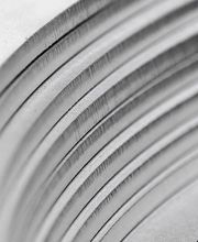 Nahaufnahme eines metallischen, geriffelten Zylinders mit eckigen Details in Grautönen.