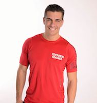 Mann in rotem T-Shirt mit Aufschrift "Personal Trainer", lächelt vor weißem Hintergrund.