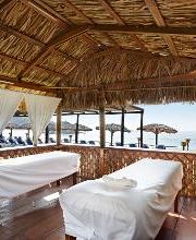 Camas de masaje en una palapa con vista al mar y techada con hojas de palma.