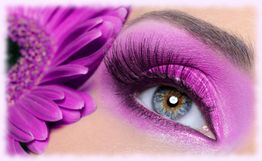 Auge mit violettem Lidschatten und Wimpern, daneben eine lila Blume.