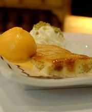 Postre en plato blanco: flan con helado de mango y nata montada.