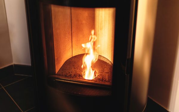 Ein Holzofen, ausgekleidet mit Schamotte. In der Mitte des Brennraumes lodert eine Flamme.