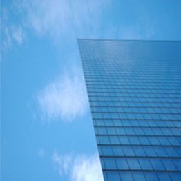 Tall modern glass building against a blue sky with light clouds.
