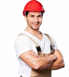 Man in a red hard hat and overalls smiling with arms crossed, isolated on a white background.