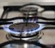 Lit gas stove burner with blue flame.