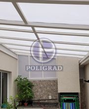 Teto de pergolado coberto, plantas e cadeiras empilhadas ao lado de uma churrasqueira.