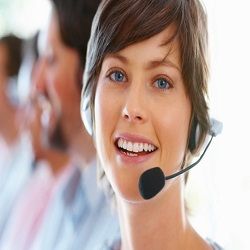 Vrouw met headset glimlacht terwijl ze werkt als klantenservicemedewerker.