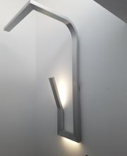 Lámpara de pared moderna de metal gris en forma de L, emite luz suave desde su base.