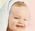 Lächelndes Baby mit Kapuze, leicht zur Seite gedreht.