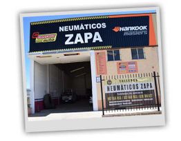 Taller de neumáticos con letrero "Neumáticos ZAPA" y logos de marcas en la fachada.