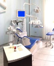 Studio dentistico con sedia blu, attrezzature odontoiatriche e monitor, illuminato dalla finestra.