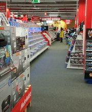 Negozio di elettronica con scaffali pieni di stampanti HP e accessori. Personale sullo sfondo.