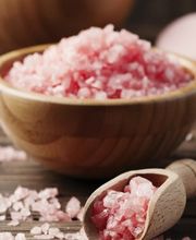 Rosa Salz in Holzschalen und einem Löffel auf Holztisch.