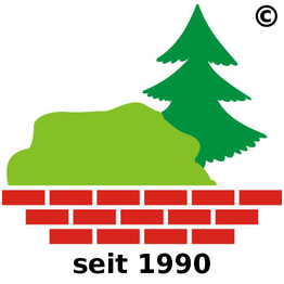 Eine grüne Hecke und ein Tannenbaum stehen hinter einer kurzen roten Ziegelmauer.