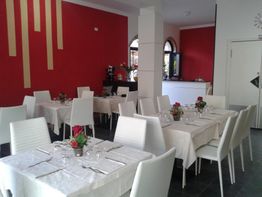 Ristorante elegante con tavoli apparecchiati, pareti rosse e decorazioni floreali.