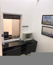 Sala de espera com balcão, duas cadeiras e fotos na parede. Janela de atendimento à esquerda.