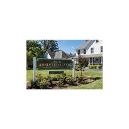 Assisted living facility sign in front of a white house with a well-maintained garden.