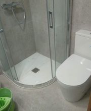 Baño moderno con ducha de cristal, inodoro, bidé y balde verde.