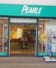 Winkelgevel van Pearle Opticiens met posters en een groene luifel.