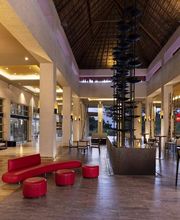Vestíbulo moderno con techo alto, muebles rojos y bar iluminado.