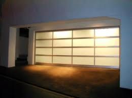Illuminated glass-panel garage door at night.