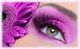 Auge mit violettem Lidschatten und Wimpern, daneben eine lila Blume.