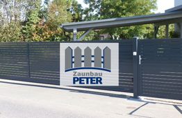 Ein graues Tor mit dem Logo der Firma "Zaunbau Peter" und Bäumen im Hintergrund.