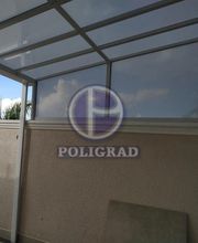 Cobertura em alpendre com estrutura metálica e telhado translúcido sob céu nublado.