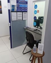Recepção de escritório com cadeira, balcão de atendimento e álcool gel sobre um banco.