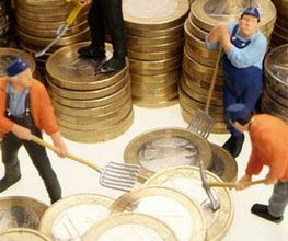 Miniaturfiguren arbeiten mit Harken auf Münzstapeln, symbolisieren Finanzen und Arbeit.