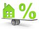 Green house and percent symbol balanced on a seesaw, illustrating mortgage interest rates.