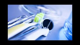 Strumenti dentali e spazzolino verde su superficie blu sfocata, ambiente medico.