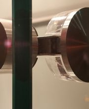 Metallbeschlag an einer gläsernen Duschtür in Nahaufnahme.