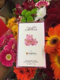 Parfümverpackung „Althea“ von Sabryna, umgeben von bunten Gerbera-Blüten und anderen Blumen.