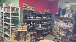 Ein Geschäft mit Regalen voller Gewürze, Öle und Leckereien auf Holztischen und Regalen.