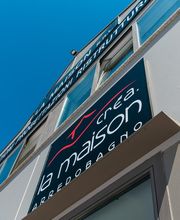 Edificio con insegna "La Maison" e cielo blu sullo sfondo.