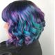 Shoulder-length hair with vibrant purple, blue, and teal curls.