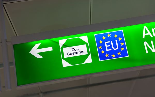 Ein beleuchtetes grünes Schild an einem Flughafen, das darauf hinweist wo sich die Zollkontrolle befindet.