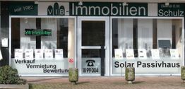 Vorderseite eines Immobilienbüros mit Angeboten zu Verkauf, Vermietung und Solar-Passivhäusern.