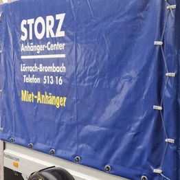 Blauer Planenanhänger mit Werbung: STORZ Anhänger-Center, Lörrach-Brombach, Miet-Anhänger.