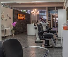 Moderner Friseursalon mit Waschtischen, Spiegeln und stilvollen Dekorationen unter Kronleuchtern.
