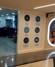 Corredor de agência de câmbio com displays informativos nas paredes iluminadas por luzes circulares.