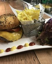 Burger mit Pommes und Salat auf einem weißen Teller, dekoriert mit Ketchup und Senf-Tupfen.